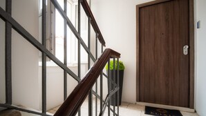 Un escalier avec des rampes en métal, une porte en bois et une plante en pot.