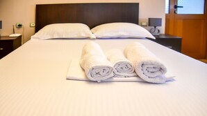 A neatly made bed with white linens, two rolled towels, and two pillows. - Hotel Sofra (Gjirokastër)