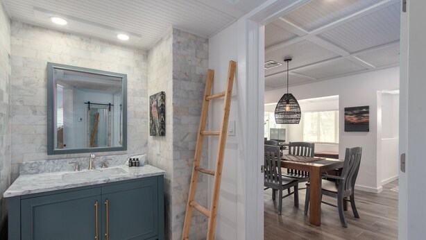 Un baño moderno con un lavabo de mármol, una escalera de madera y una zona de comedor con mesa y sillas de madera.