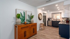 Una cocina moderna con armarios de madera, una isla central y un comedor con un taburete.