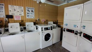 Une laverie équipée de plusieurs machines à laver, avec des panneaux d’information et un mur carrelé.