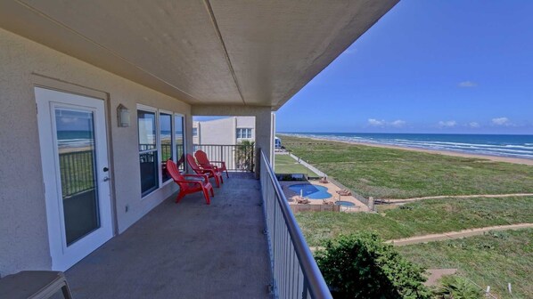 Un balcon avec vue sur l’océan, des chaises rouges et un espace piscine.
