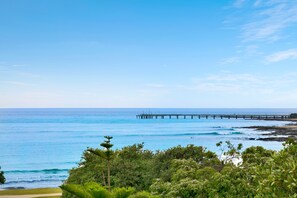 A coastal view with a pier extending into the sea, surrounded by lush greenery. - Waterfront Two (Lorne)