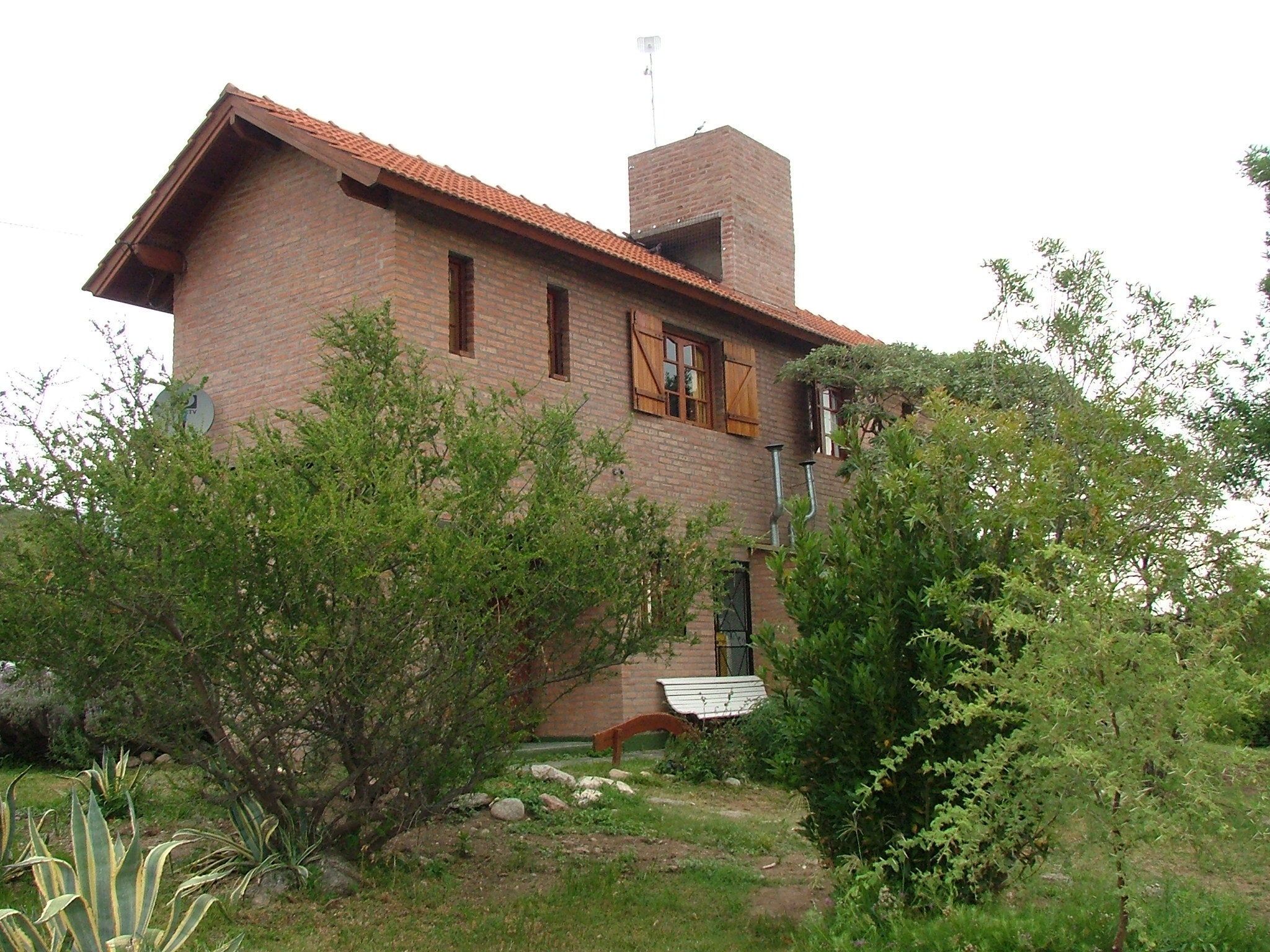 Una casa a due piani in mattoni con tetto in tegole rosse, un camino e un'antenna parabolica.
