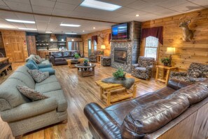 Ein gemütliches Lodge-Interieur mit Kamin, Ledersofas und einem an der Wand befestigten Fernseher.
