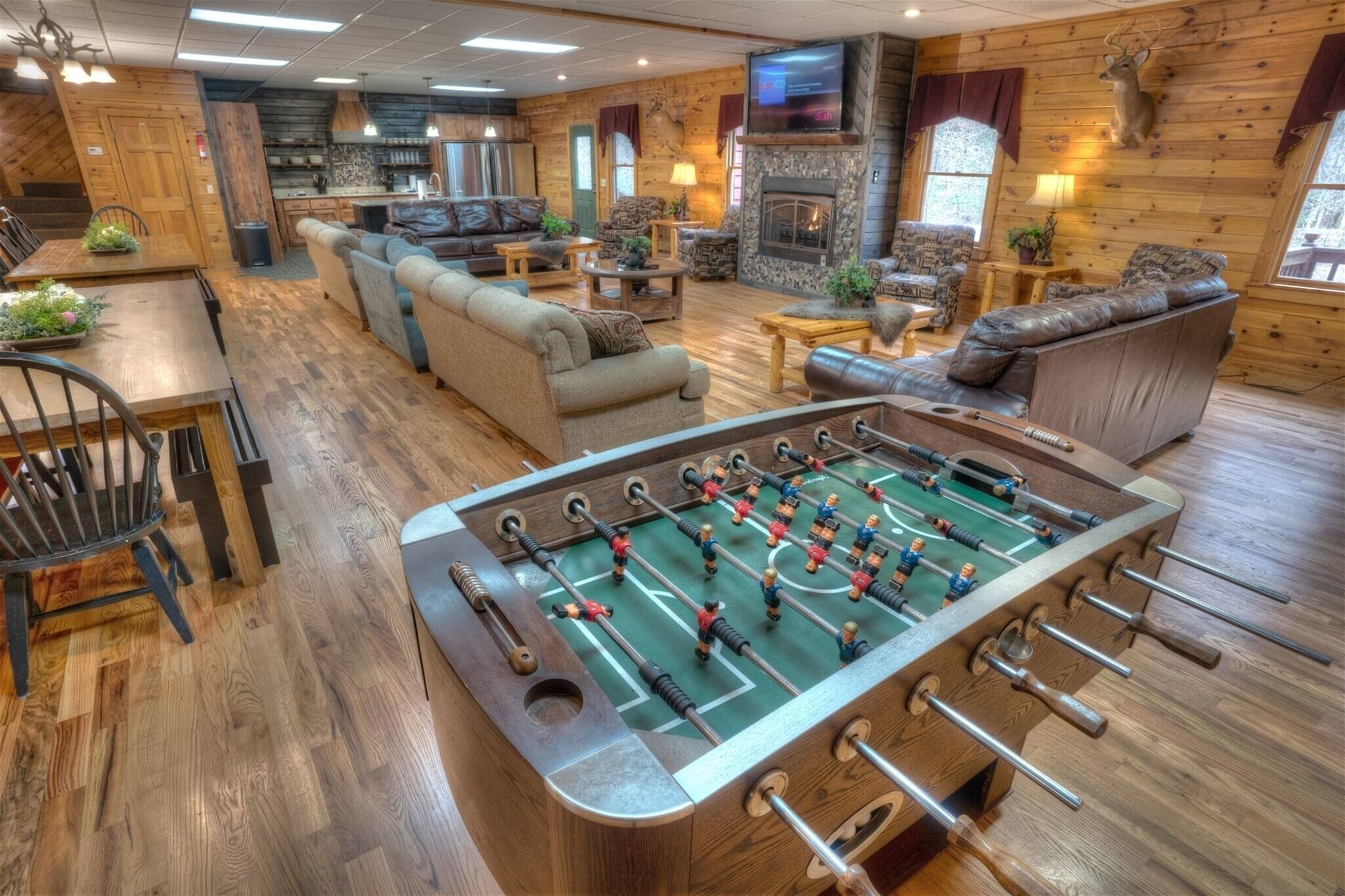 A cozy room with a foosball table, sofas, a fireplace, and a television.
