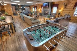 A cozy room with a foosball table, sofas, a fireplace, and a television.