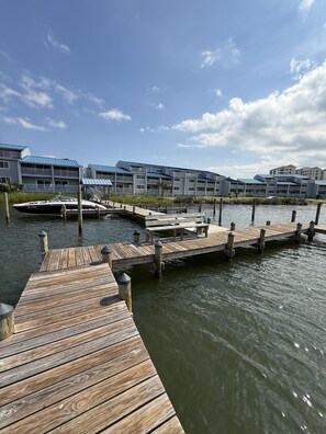 A waterfront property with a wooden dock, a marina, and a row of buildings with balconies.
