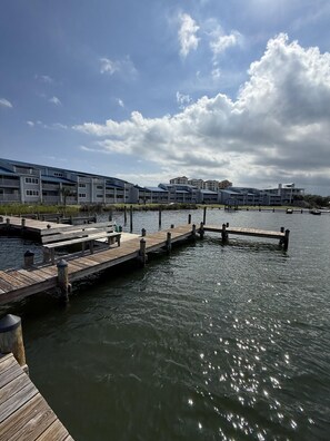 A waterfront property with a dock extending into the water, surrounded by buildings with balconies. - C21 Sundown Riverside Condominiums (Pensacola)