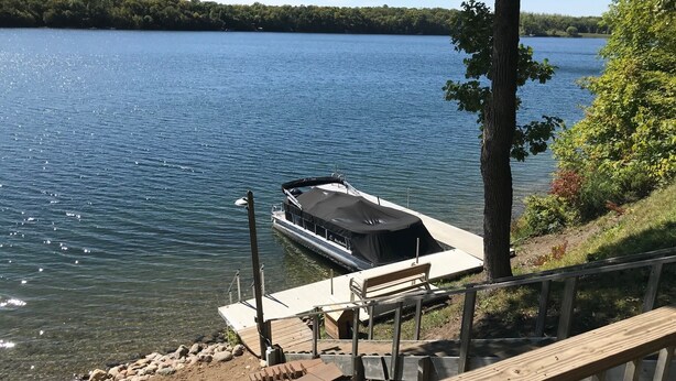 Un muelle con un barco, una cubierta de madera y vistas a un lago.