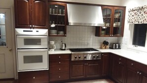 Una cocina con armarios de madera oscura, una estufa de acero inoxidable y un salpicadero blanco de azulejos.