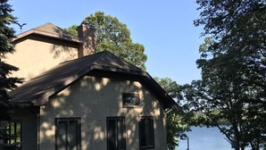 Una casa de un piso con techo inclinado, una chimenea y un pequeño porche.