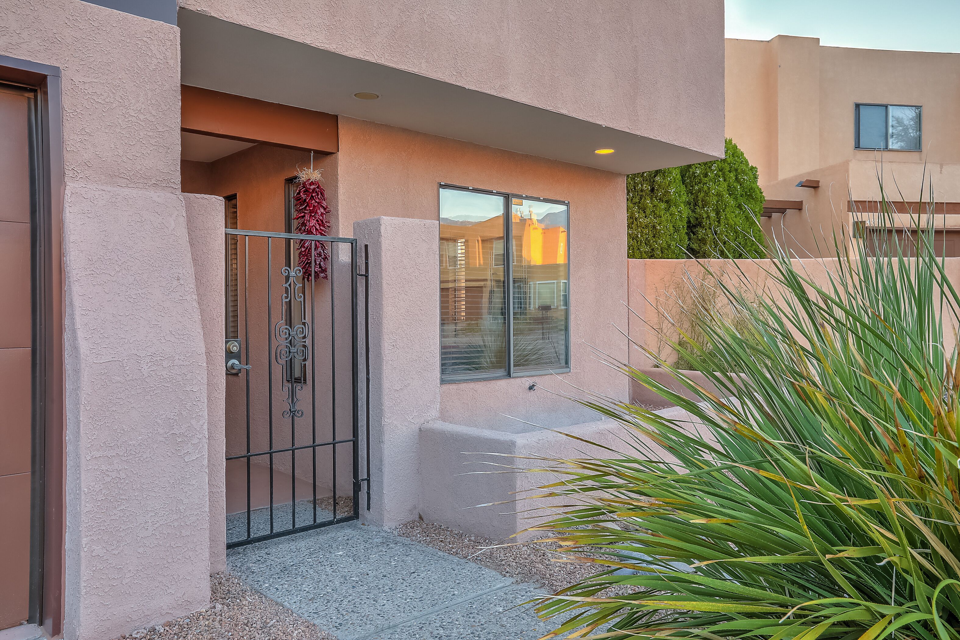 A modern building with a stucco exterior, a gated entrance, and a small porch area.