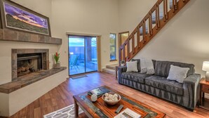 A spacious living room with a fireplace, a sofa, a coffee table, and a staircase. - Charming home in the Albuquerque foothills (Albuquerque)