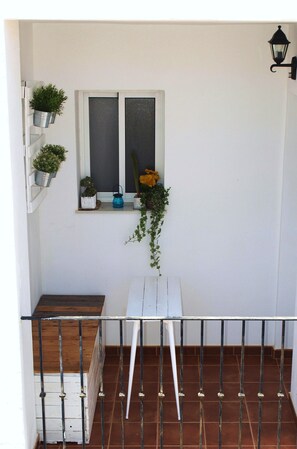 Ein Balkon mit weißem Tisch, Blumentöpfen und einem Fenster mit Blick.