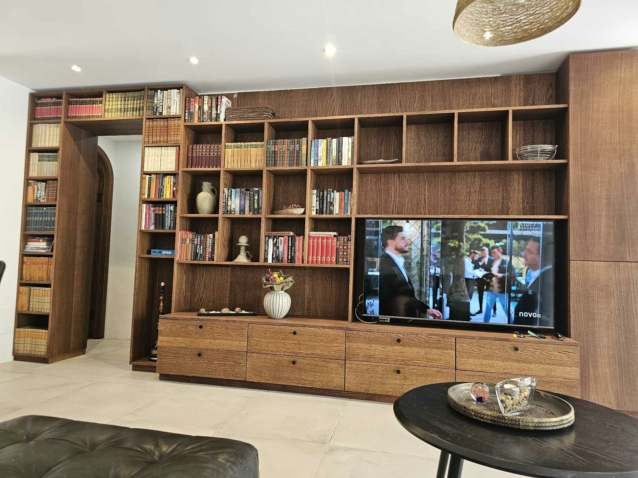 En stue med stort tv, træbogreoler, sofa og sofabord.