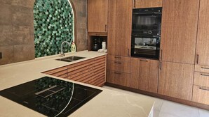 Eine moderne Küche mit Holzschränken, einem eingebauten Backofen und einer auffälligen, sechseckigen Rückwand in Grün.
