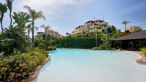 Ein Pool mit geschwungener Kante, umgeben von üppiger Vegetation und Palmen.