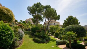 Ein gepflegter Garten mit ordentlich gestutzten Rasenflächen, verschiedenen Sträuchern und einigen Bäumen.