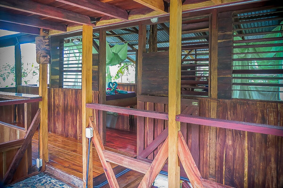 A wooden structure with a staircase and a window with green blinds.