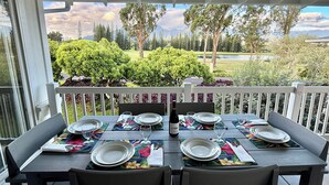 Una mesa de comedor al aire libre con sillas, platos, vasos y una botella.
