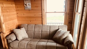 A beige sectional sofa with two cushions in a wooden cabin-style room with a window. - Lakeside Paradise on Berlin  (Deerfield)
