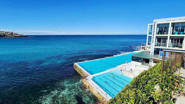 A hotel with a pool overlooking the sea, a lifeguard tower, and a view of the coastline. - Breathtaking Ocean Views - 2 bedroom apartment with parking (Tamarama)
