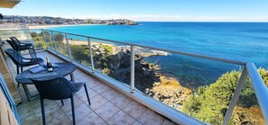 Een balkon met uitzicht op zee en een stadsbeeld.