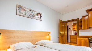 A hotel room with a wooden headboard, two beds, a painting on the wall, and wooden cabinets.