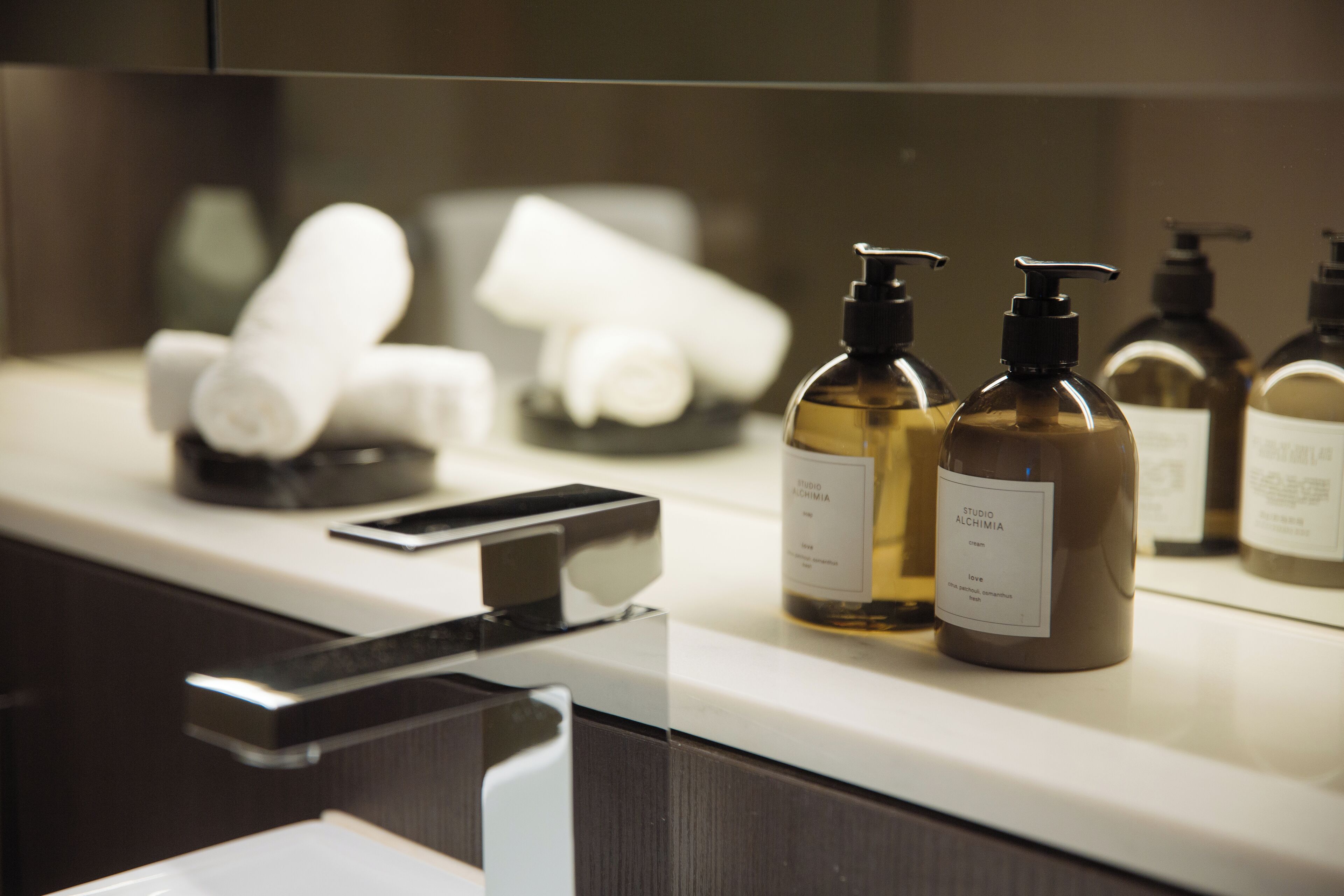 A bathroom counter with toiletries, including bottles and a smartphone.