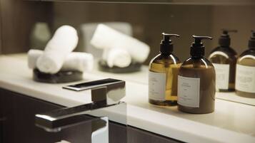 A bathroom counter with toiletries, including bottles and a smartphone.