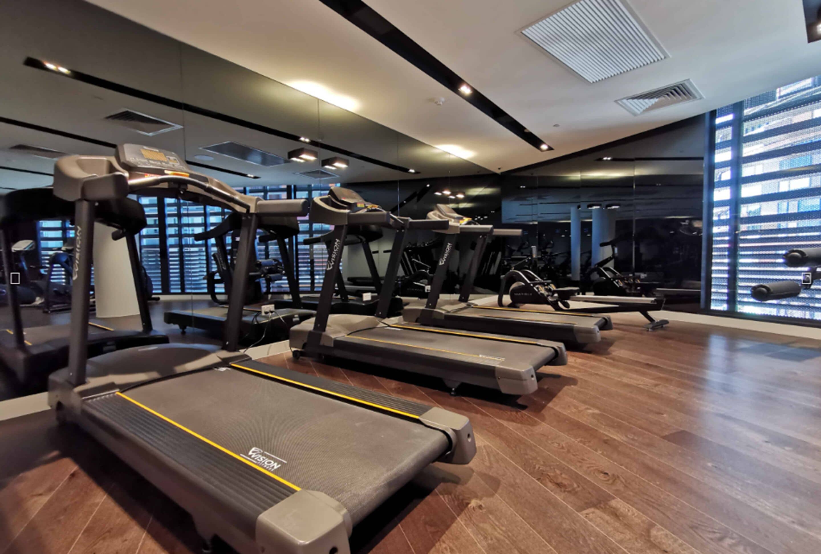 A gym with treadmills, exercise equipment, and large windows.