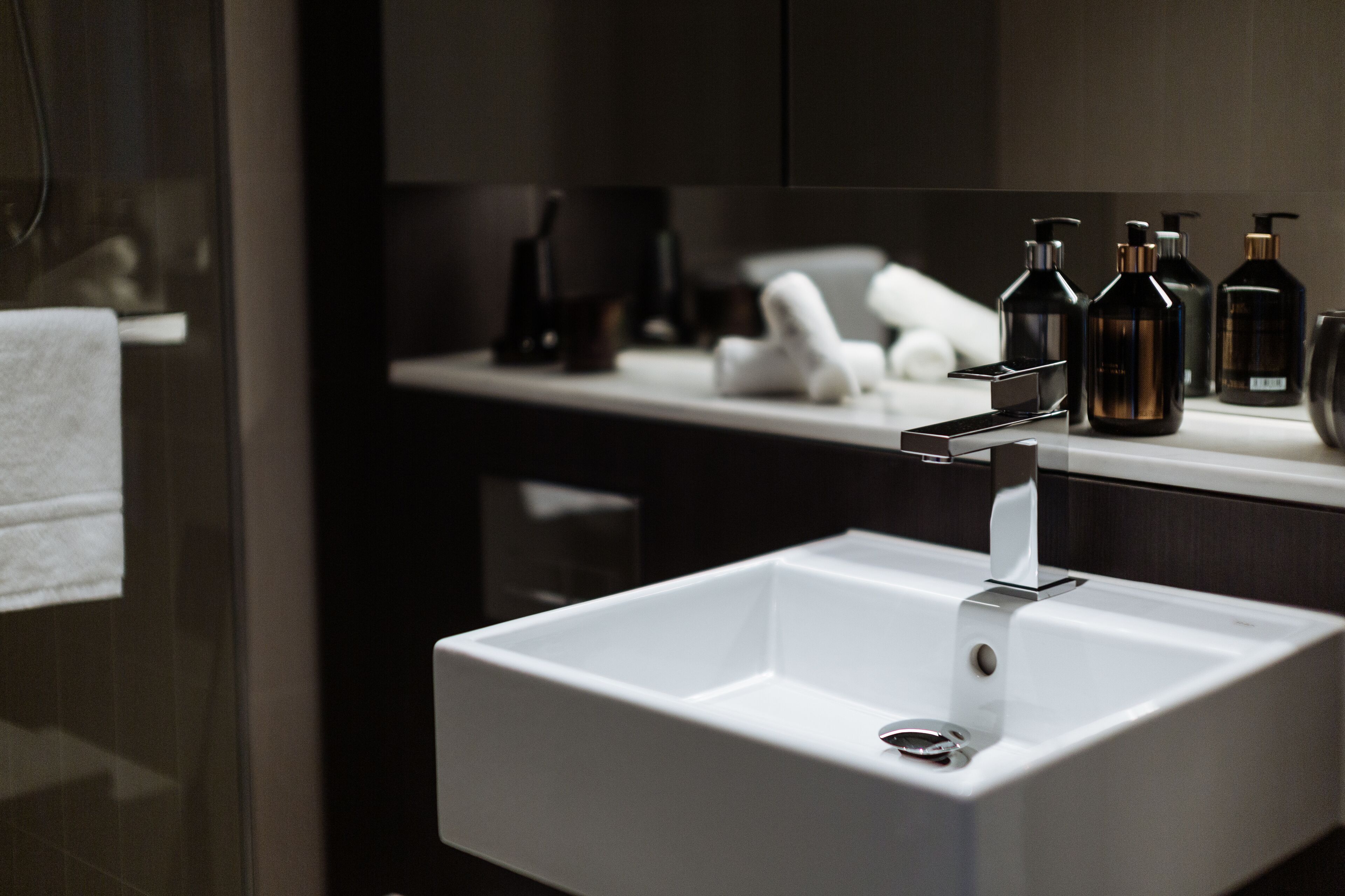 A modern bathroom with a white sink, dark cabinetry, and a mirror.