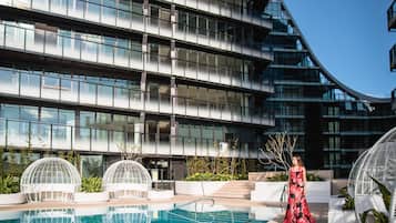 A modern building with a pool, white spherical structures, and a woman in a dress.