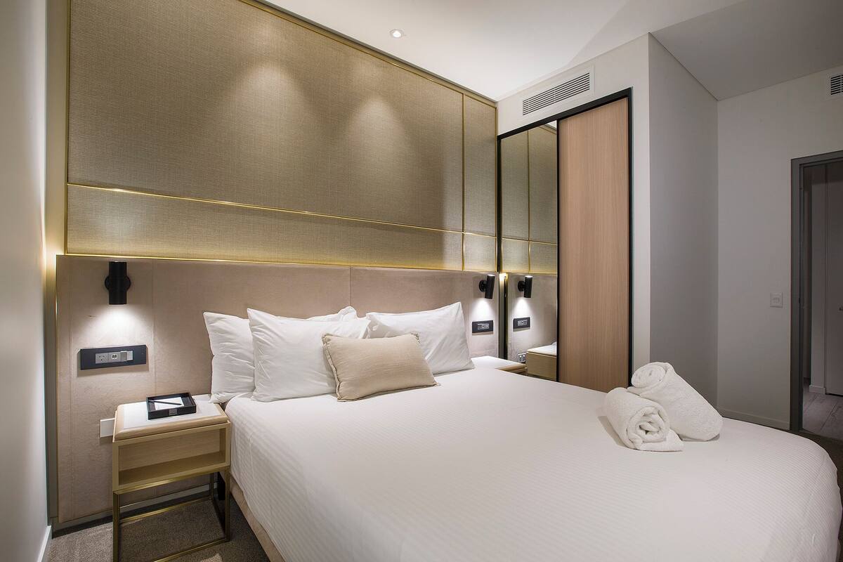 Une chambre d’hôtel avec un grand lit, une table de chevet, un miroir et une porte.
