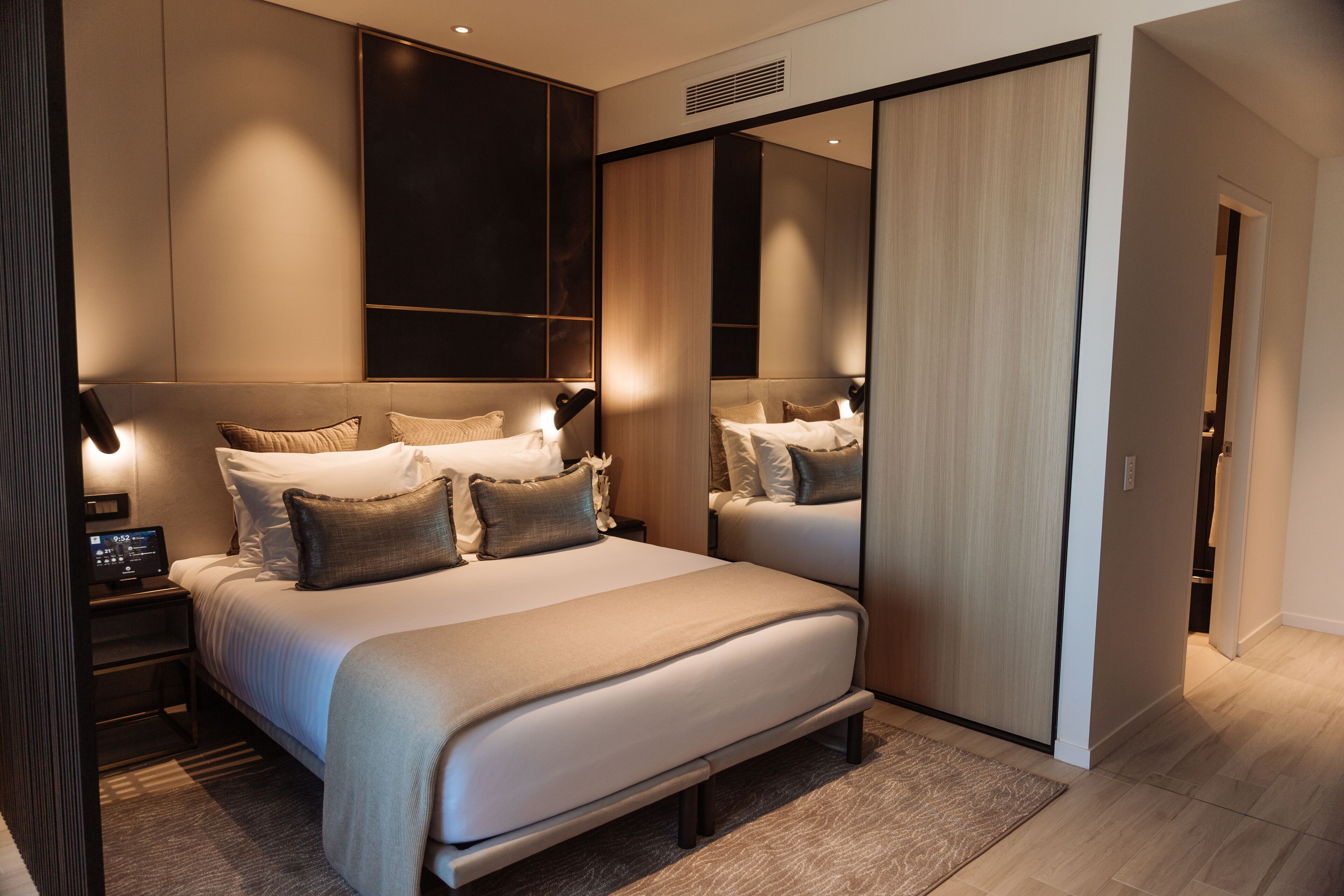 Un dormitorio moderno con una cama grande, mesitas de noche y un armario con espejo.