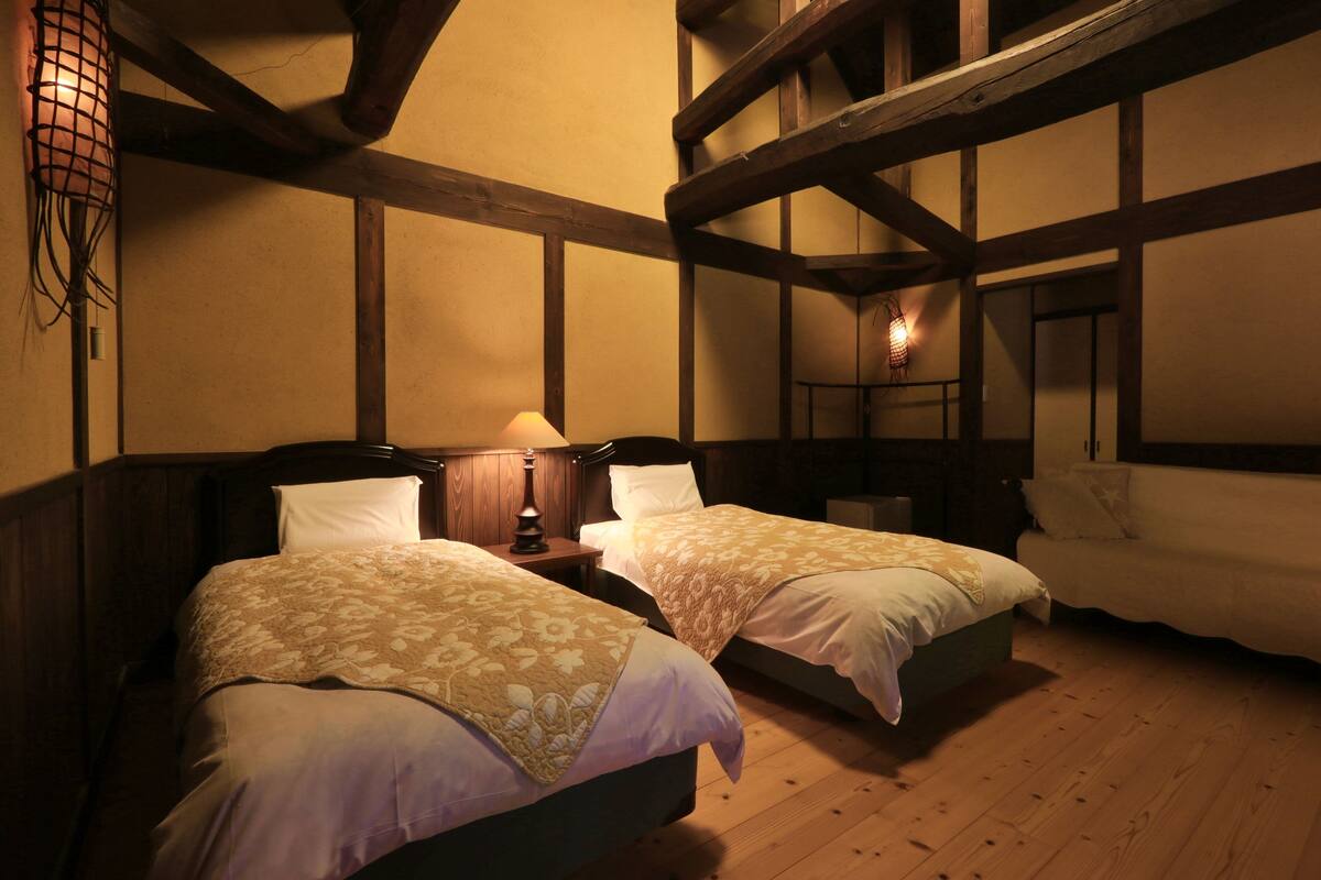 A room with two beds, wooden beams, and a hanging light fixture.