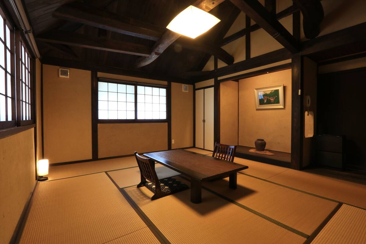 A traditional Japanese room with tatami flooring, a low table, and sliding doors.