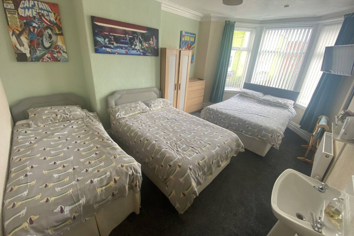 Habitación de hotel con dos camas, baño y ventana con cortinas.