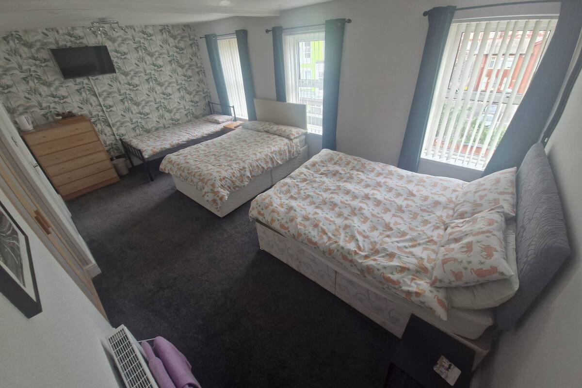 Un dormitorio con dos camas individuales, un aparador, un televisor y una ventana con cortinas.