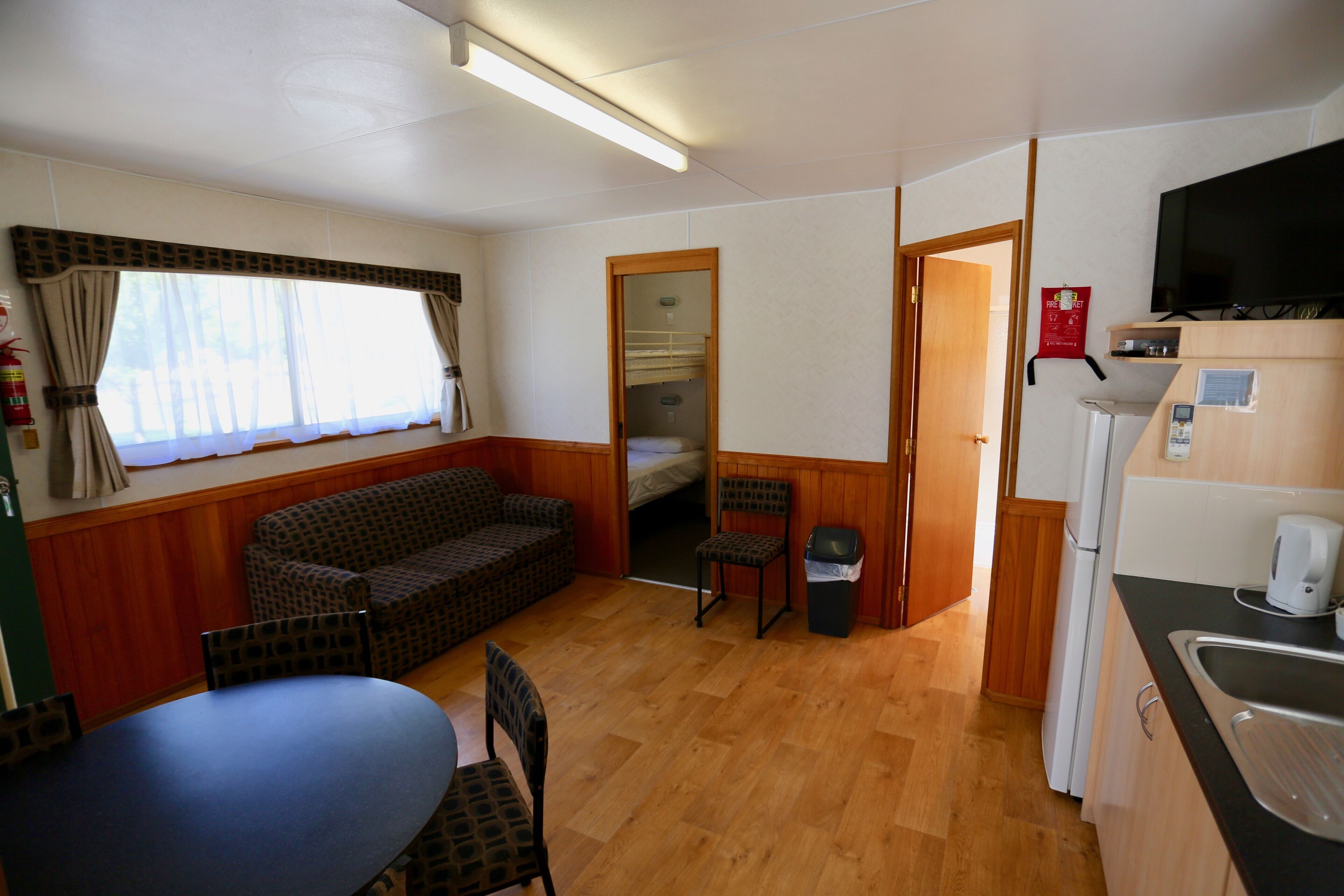 Een knus verblijf met een bank, stoelen, een tafel, een kitchenette en een televisie.