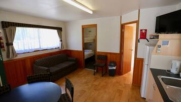 Een knus verblijf met een bank, stoelen, een tafel, een kitchenette en een televisie.
