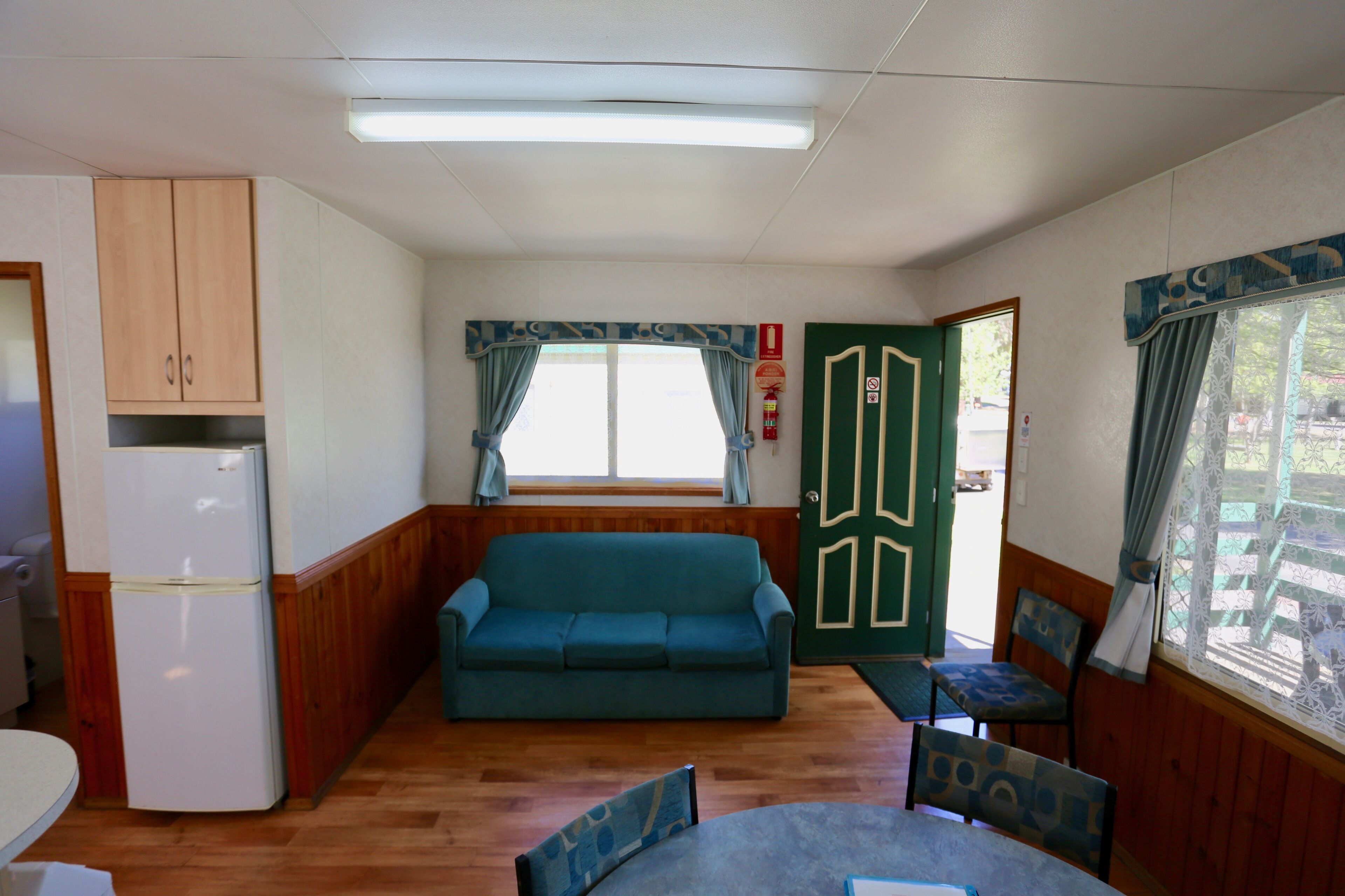 Una habitación compacta con kitchenette, un sofá, una mesa de comedor y una silla.