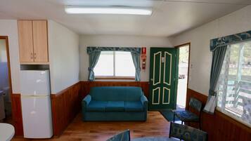 Una habitación compacta con kitchenette, un sofá, una mesa de comedor y una silla.