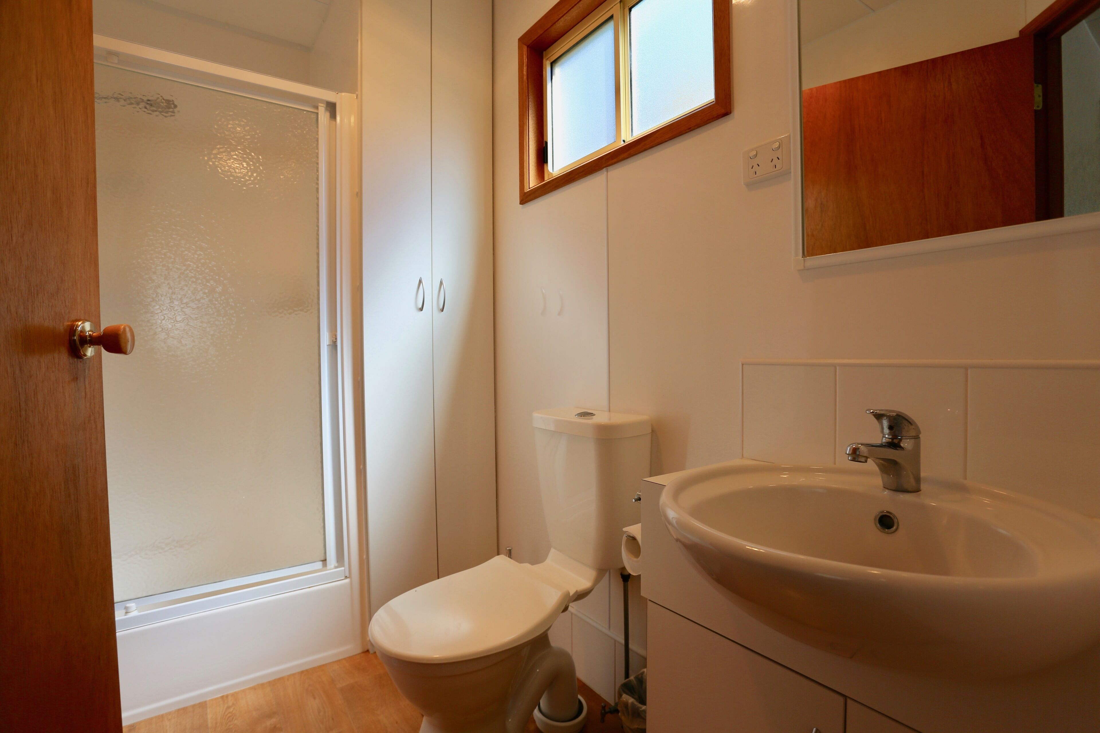 A bathroom with a toilet, sink, and a window above the mirror.