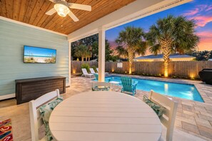 A covered outdoor area with a pool, seating, and a ceiling fan. - Five O'clock Somewhere... 4BR/3.5 BA with Private Pool. PCB West End. Sleeps 14 (Panama City Beach)