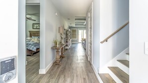 Un corridoio con pavimento in legno, una scala e un letto con copriletto bianco e blu a quadri.