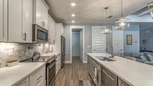 Una cucina moderna con mobili bianchi, elettrodomestici in acciaio inossidabile e pavimento in legno.
