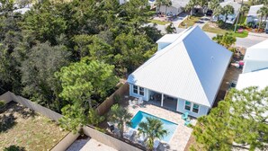 Una casa circondata da alberi e con una piscina, immersa in un giardino recintato.