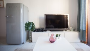 A modern living room with a flat-screen TV, a silver refrigerator, a white coffee table, and a potted plant. - Apartamanto with terrace, free WiFi, communal pool in Puerto Rico (Mogán)